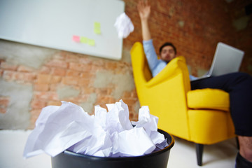 Modern freelancer throwing crumpled paper into trash bin