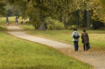 Two old ladies and two cyclists in the distance on autumn path - Unidentified people with their backs to the beholder