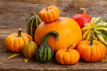 harvest of orange and green pumpkins with fall leaves on wooden table