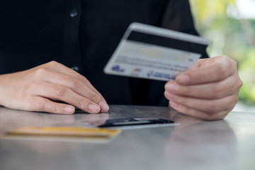 Closeup image of a woman's hand holding and looking at credit cards on the table