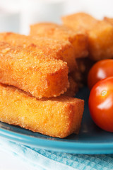 Fried cheese sticks with tomatoes on a blue plate