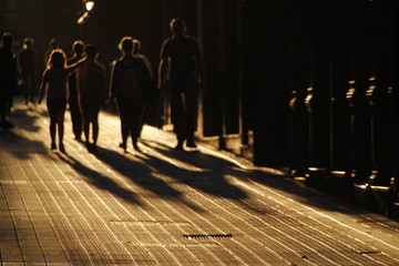 Grupo de personas caminando por la calle en una tarde de verano - obrazy, fototapety, plakaty
