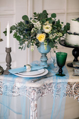 beautiful decorate table with candles, vase with flowers and wedding cake on the table in studio