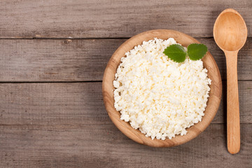 Cottage cheese in a wooden bowl on old wooden background with copy space for your text. Top view