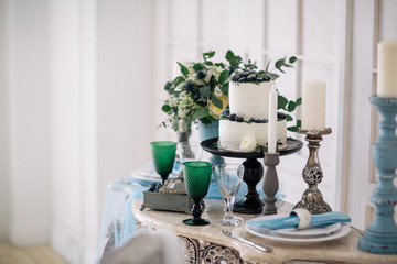beautiful decorate table with candles, vase with flowers and wedding cake on the table in studio