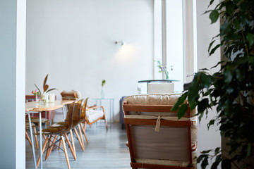 Interior of modern restaurant with stylish design: panoramic windows, wooden table, cozy chairs