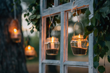 Lamps  with candles  are  hanging  on a tree at night. Wedding night decor.