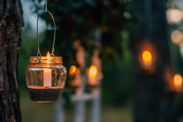 Lamp  with candle  is  hanging  on a tree at night. Wedding night decor.