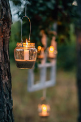 Lamp  with candle  is  hanging  on a tree at night. Wedding night decor.