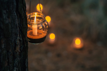 Lamp  with candle  is  hanging  on a tree at night. Wedding night decor.