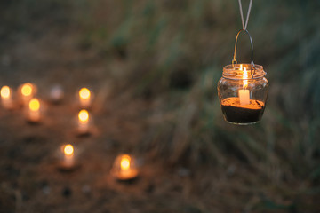 Lamp  with candle  is  hanging  on a tree at night. Wedding night decor.