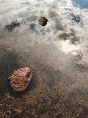 Rocks in Still Water Reflecting Sky - 167818032