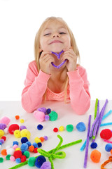 fillette 6 ans jouant avec des pompons de couleurs et des fils chenille © mariesacha