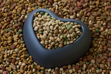Obraz premium Heart pet bowl filled by dry pet food.