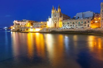 Fototapeta na wymiar Balluta Bay and Neo-Gothic Church of Our Lady of Mount Carmel, Balluta parish church, during evening blue hour, Saint Julien, Malta