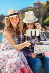 Funny female friends on vacation taking selfies on the beach with a smart phone