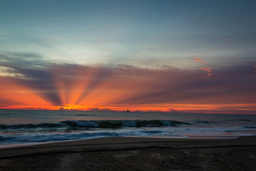 beautiful god ray of sun breaking through clouds at sunrise over the ocean  