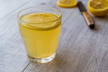 Lemon Liqueur Limoncello with lemon on white wooden surface.