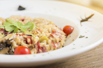 Fragrant Pilau/Pulav / pilaf /pilaf, fried rice with meat and vegetables on a white plate. Isolated on a wooden table.