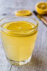 Lemon Liqueur Limoncello with lemon on white wooden surface.