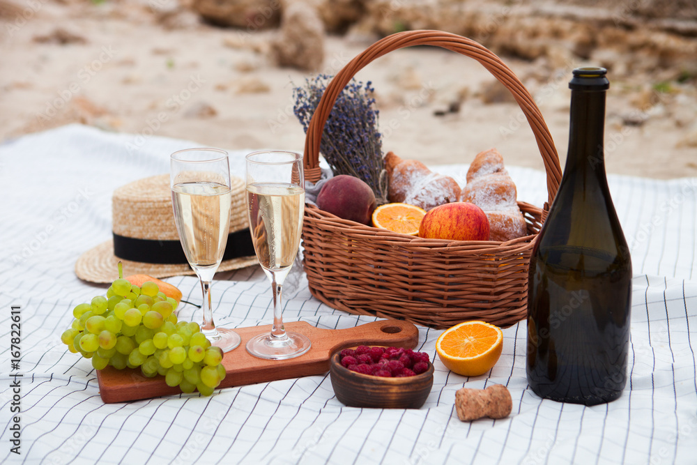 Wall mural Two glasses of champagne. Picnic on the beach at sunset in the white plaid, food and drink conception