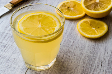 Lemon Liqueur Limoncello with lemon on white wooden surface.