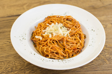 Plate of delicious spaghetti Bolognaise or Bolognese with savory minced beef and tomato sauce garnished with parmesan cheese and basil, overhead view.