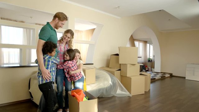 Happy family hugging indoors. People and cardboard boxes, room. Stress free moving.