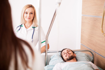 Obraz premium Sick male Patient in hospital room next to nurses. Medical and healthcare