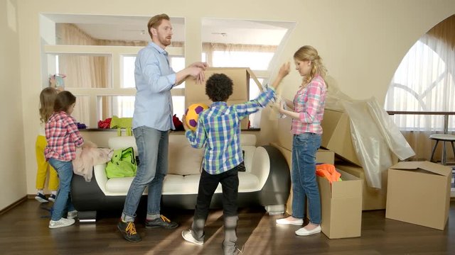 Family unpacking things from boxes. Kids and parents indoors. Pros and cons of renting.