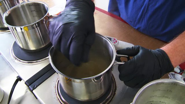 Worker stirs cannabis oil on stove