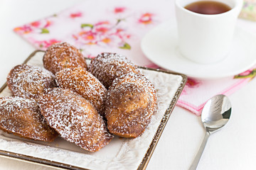 French cookies Madeleine and tea in white cup. Concept romantic Breakfast. Selective focus.