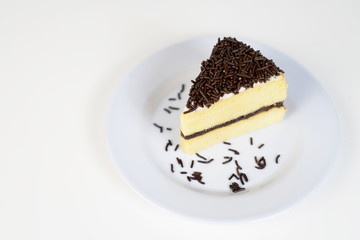 a piece of cheese cake slice topped with chocolate sprinkles rice on a white plate