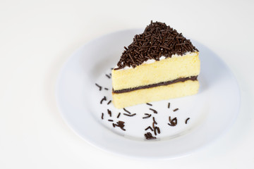 a piece of cheese cake slice topped with chocolate sprinkles rice on a white plate