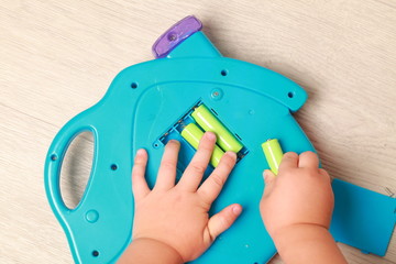 hand the child put the batteries in the blue toy