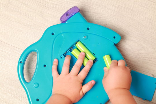 Hand The Child Put The Batteries In The Blue Toy