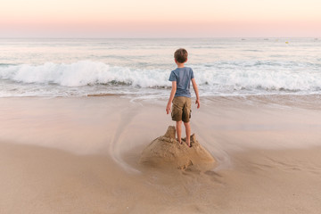 Boys standing on sandcastle waiting for the sea to destroy it