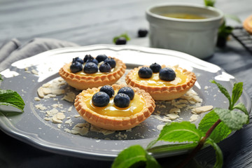 Delicious crispy tarts with blueberries and custard cream on plate