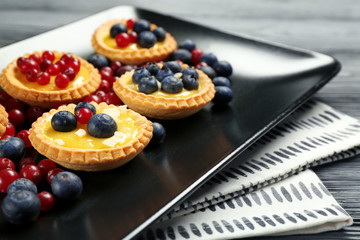Delicious crispy tarts with berries and custard cream on plate