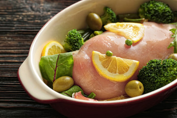 Fresh chicken breast with lemon and broccoli in baking dish, closeup