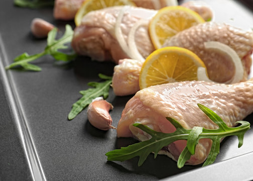 Fresh chicken legs with lemon on baking tray, closeup