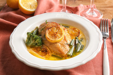 Delicious chicken breast with lemon and vegetables in plate on table