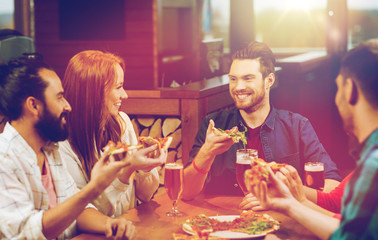 friends eating pizza with beer at restaurant