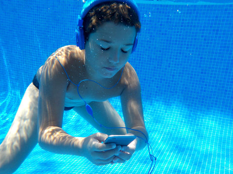 El ni&ntilde;o esta abajo del agua con su movil y auriculares
