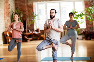 Fototapeta premium group of people doing yoga tree pose at studio