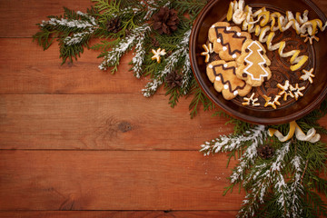 brown wooden background with Christmas design with spruce branches, pine cones and cookies