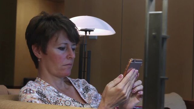 Middle aged woman texting on smartphone in corporate lobby