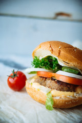 Two hamburgers with beef burger cutlet, fried onion, spinach, ketchup sauce and blue cheese in traditional buns, served on wood chopping board over bright turquoise background. Copy space
