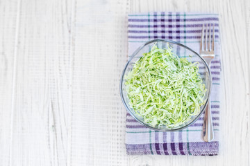 Tasty green cabbage salad in a glass bowl. Top view. Copy space. The concept is healthy food, diet, vegan.