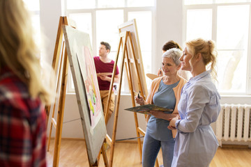 Fototapeta na wymiar artists discussing painting on easel at art school
